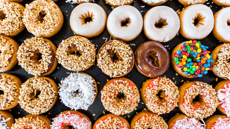 Assorted donuts with different toppings: coconut, peanuts, chocolate, M&Ms.