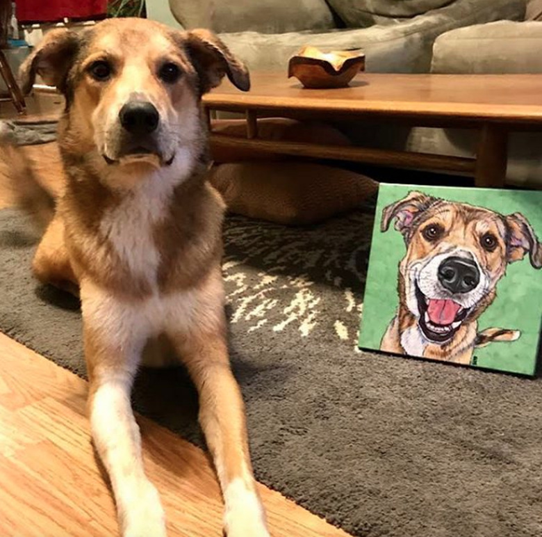 dog lying next to his custom portrait.