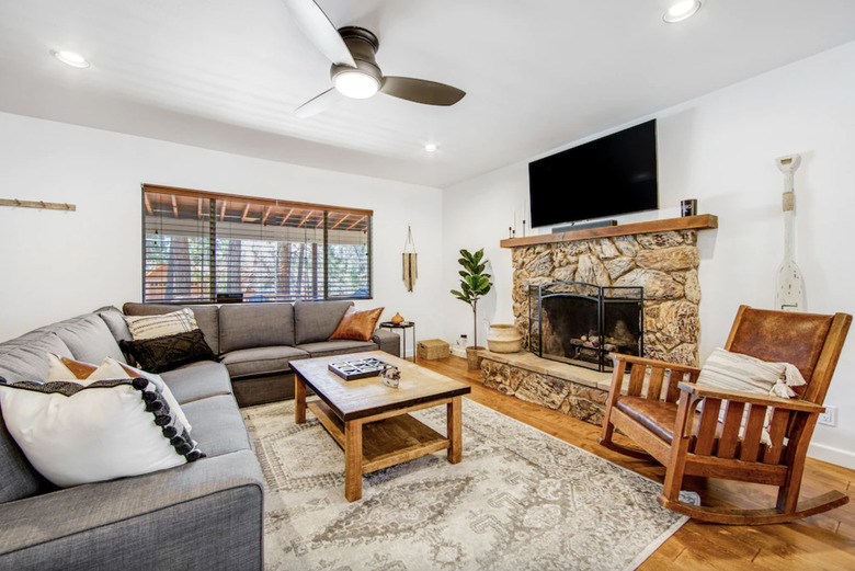 Living room of BearFoot Summit Haus showing stone fireplace with a TV above it, a large sectional, and a wooden rocking chair.