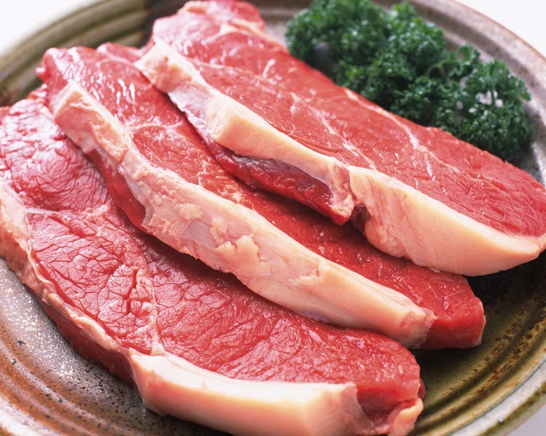 Raw beef with green leaves, high angle view