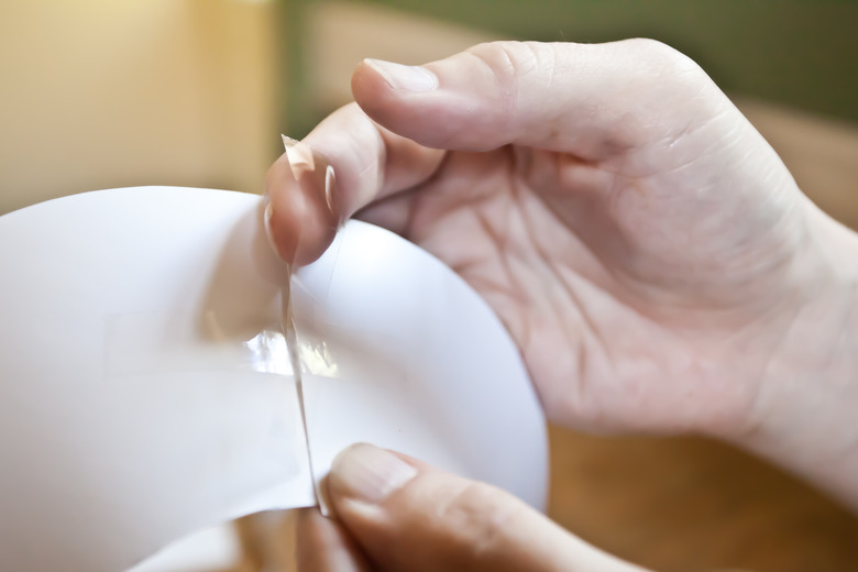 Two hands taping cardboard into a cone shape.