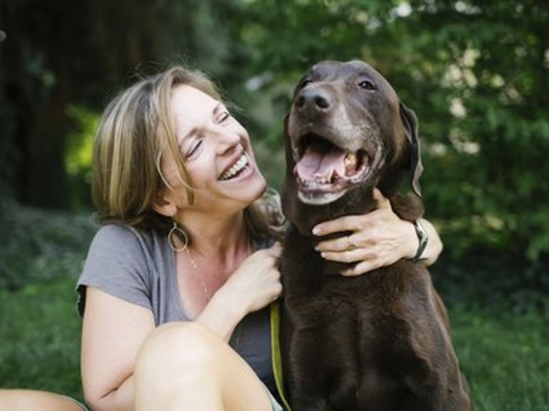 Smiling woman sitting on grass with Labrador Retriever