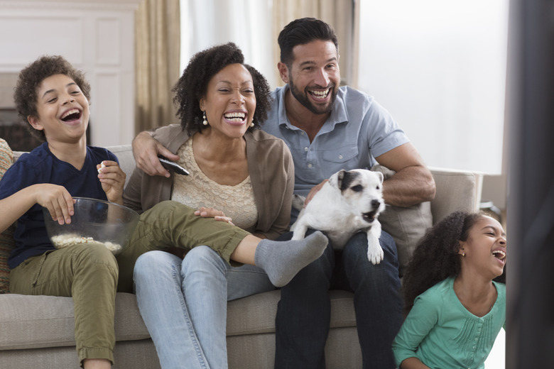 family having fun and watching tv with a barking dog on man