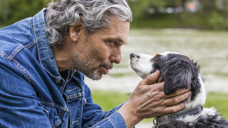 A man holds a dog by the face