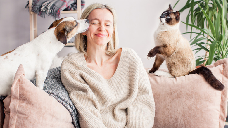 A woman on the couch in-between her cat and dog