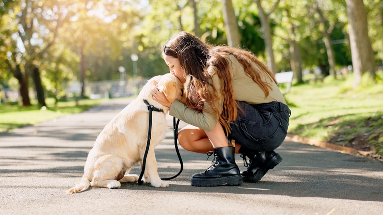 woman kissing dog on their head