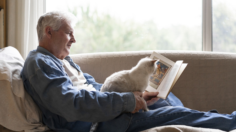 old man showing cat his book