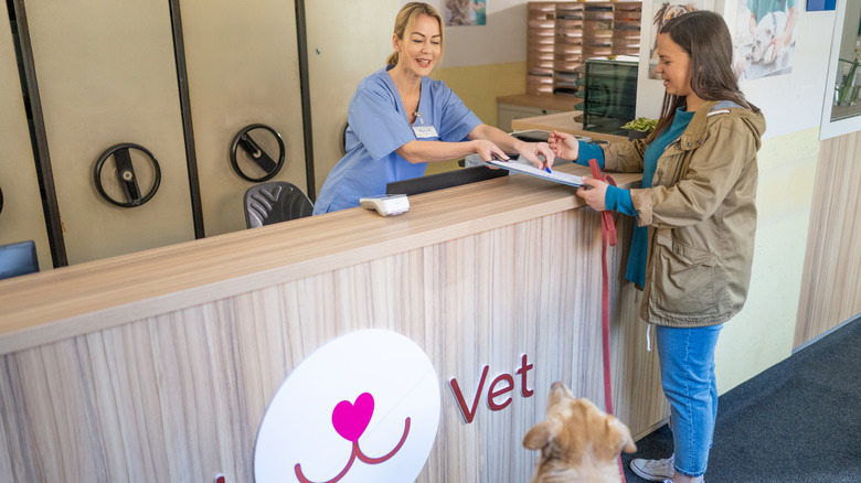 veterinary front desk worker helping a woman and her dog