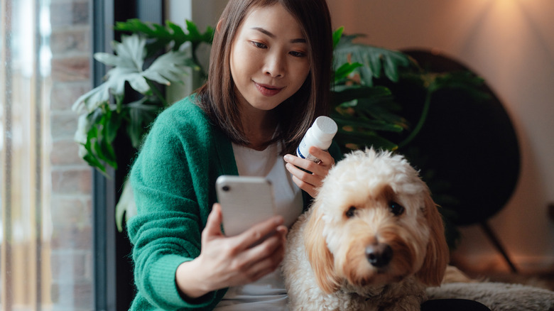 a woman holding a pill bottle during a veterinary telehealth consult