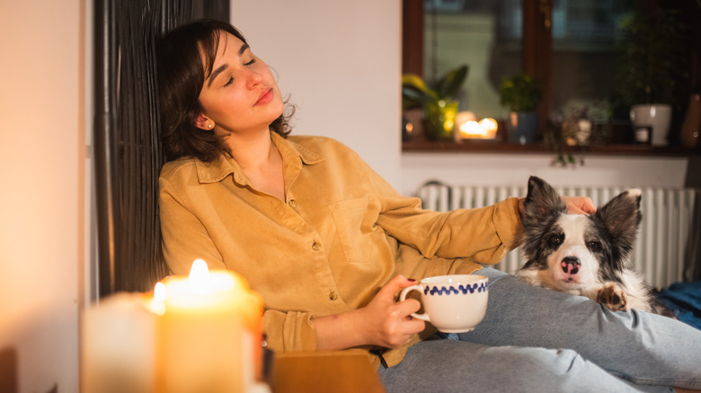 woman relaxes with dog as candle burns nearby