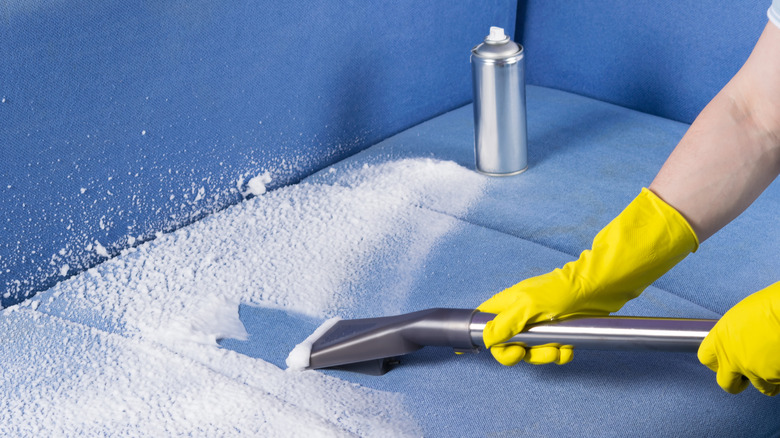 A person cleaning upholstery with chemicals and a vacuum