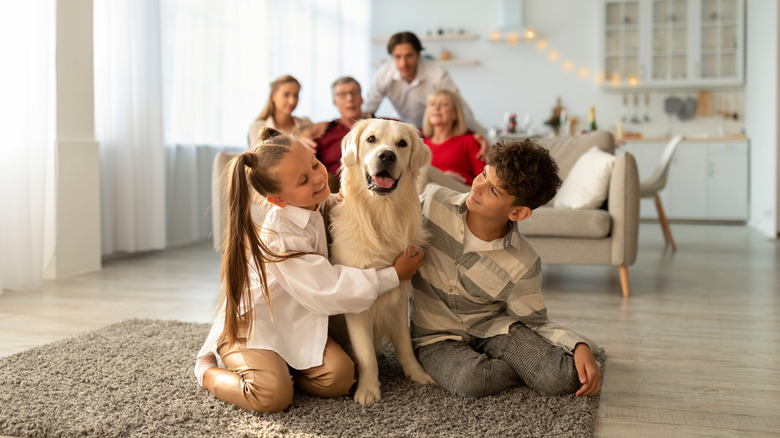 Kids hugging a golden retriever with parents and grandparents in background