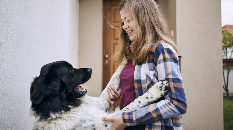 Happy dog jumping up on woman's chest outside her home