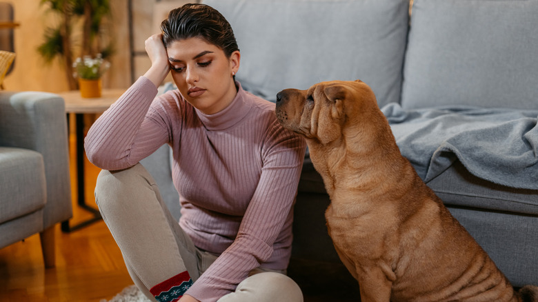 Sad woman on floor with dog next to her