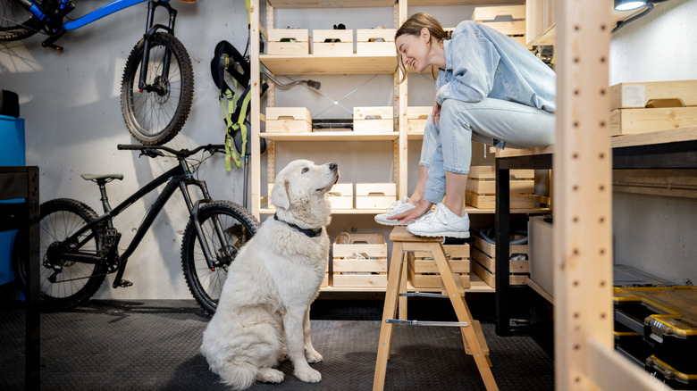 A woman sits with her Golden Retriever in the garage