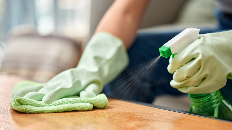 person spraying and wiping down counter