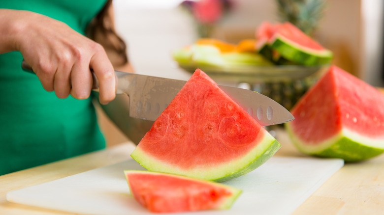 person's hand slicing watermelon