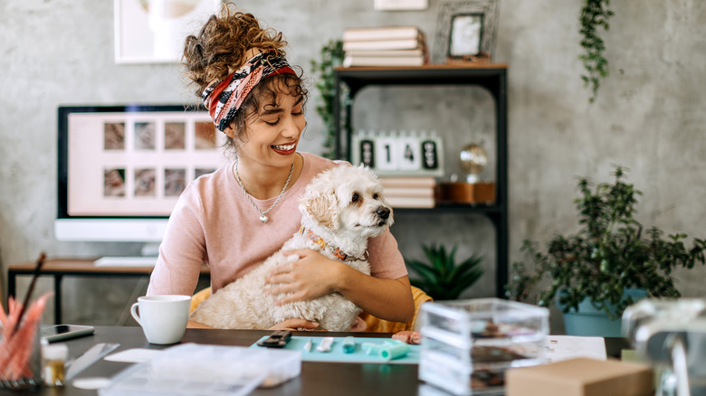 woman sitting with dog at crafting table