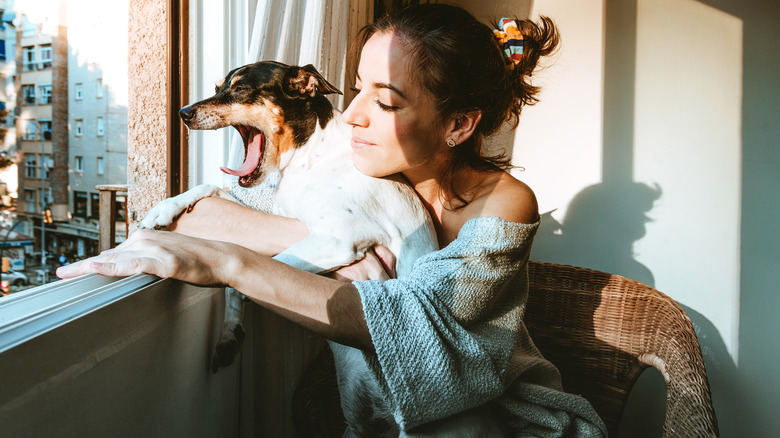 Woman holding her yawning dog