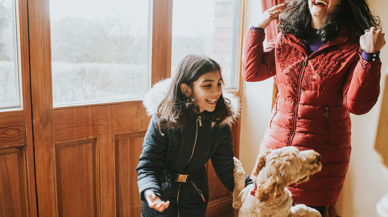 girl and woman greeted by dog