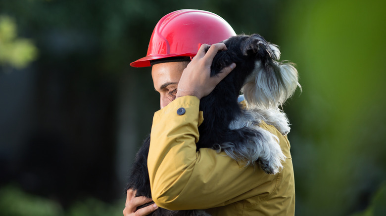 firefighter carrying a dog on his shoulder outdoors