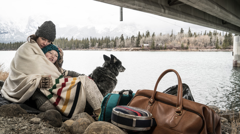 Homeless mother and daughter with their dog under a bridge