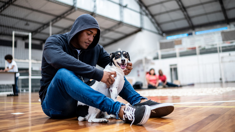 man sitting on floor with dog in community center