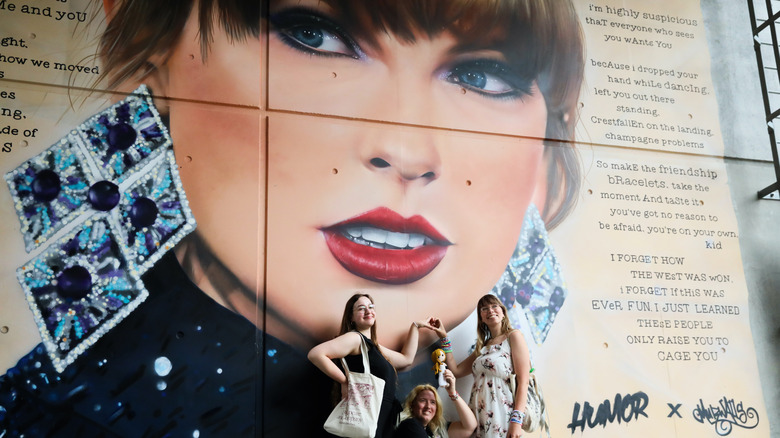 Fans standing in front a wall mural of Taylor Swift