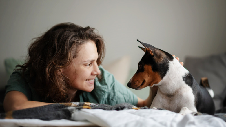 Woman lying down, looking at her basenji dog