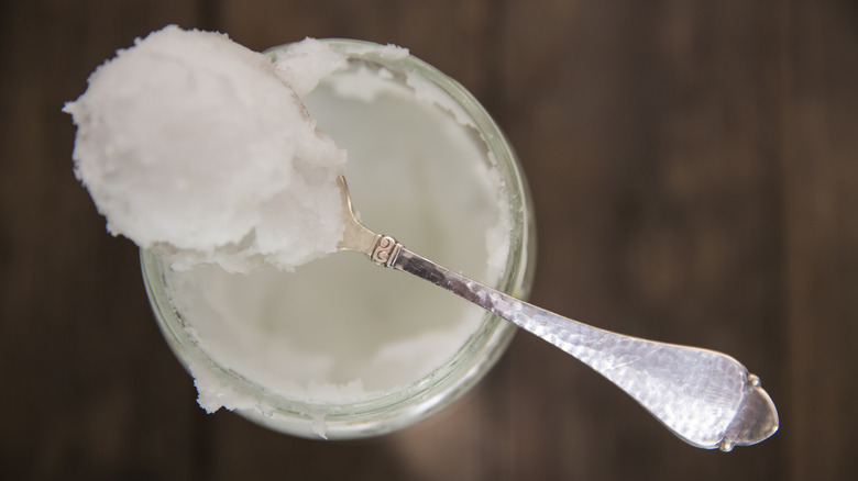 coconut oil on a spoon resting on a jar of coconut oil