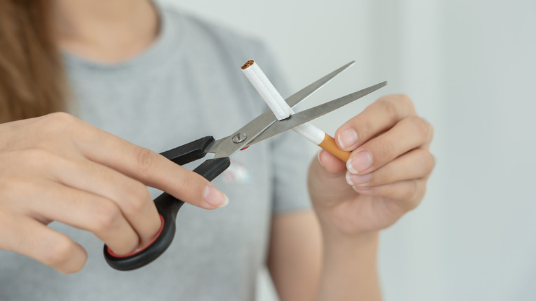 Woman cutting cigarette with scissors