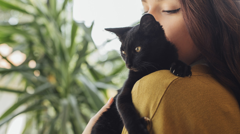 Woman holding a black kitten on her shoulder