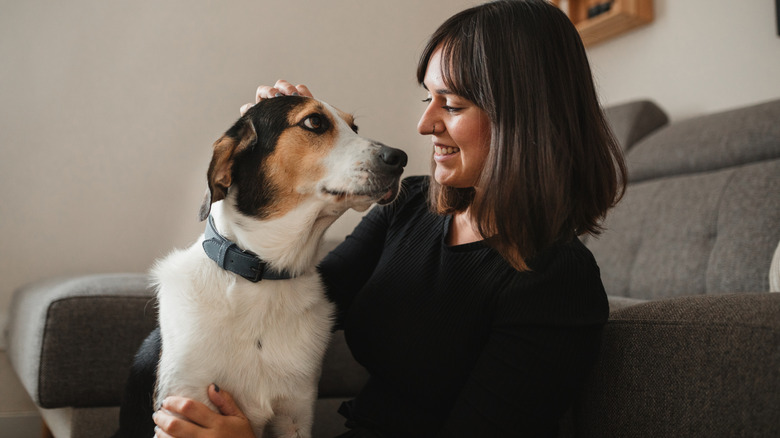 A woman petting her mixed breed dog