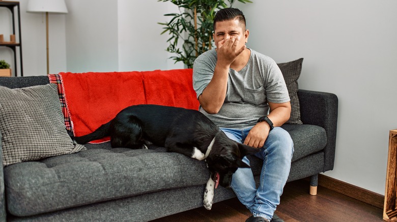 man holding his nose next to his dog