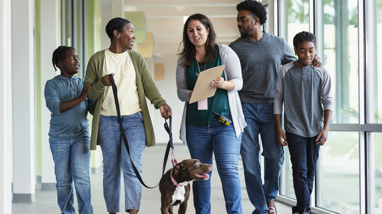 a family being helped with the dog adoption process by a shelter worker