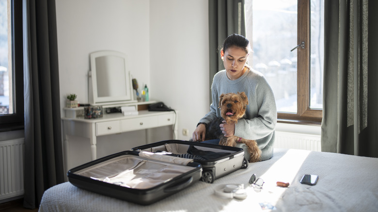 woman packing a suitcase with dog