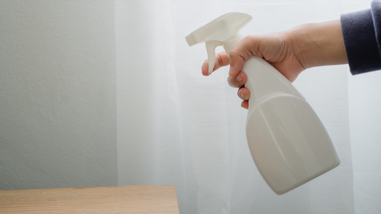 hand with spray bottle spraying a couch