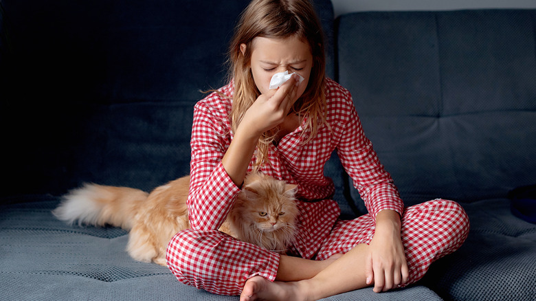 A woman with a runny nose with her cat by her feet