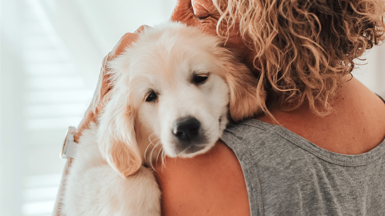 An older woman holding and hugging a white dog