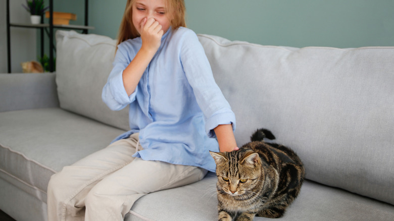 A woman sits on a couch next to her stinky cat