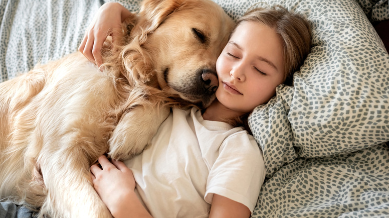 girl cuddling her dog in bed