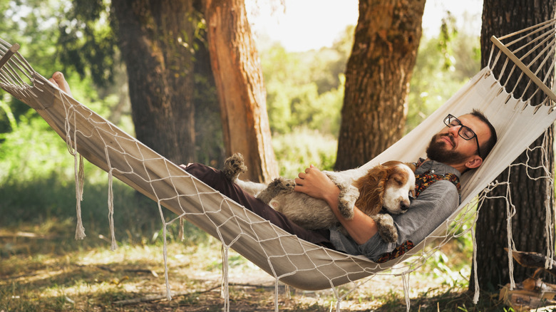 Man sleeping with his dog in a hammock