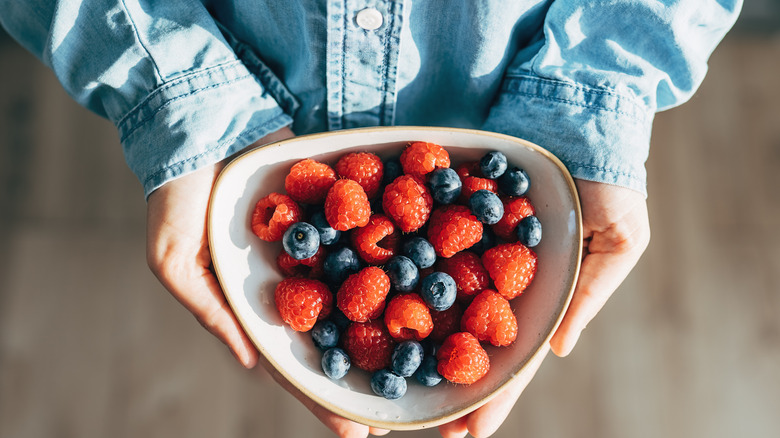 person holding cup of mixed berries