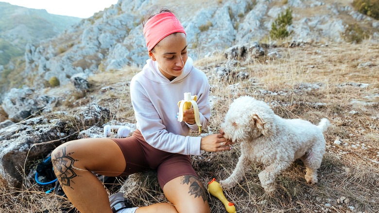 woman feeding dog a piece of banana