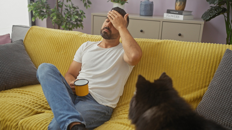 Man stressed out on sofa with dog next to him