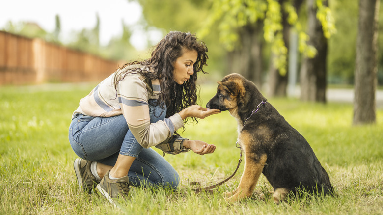 woman giving her puppy a treat outside